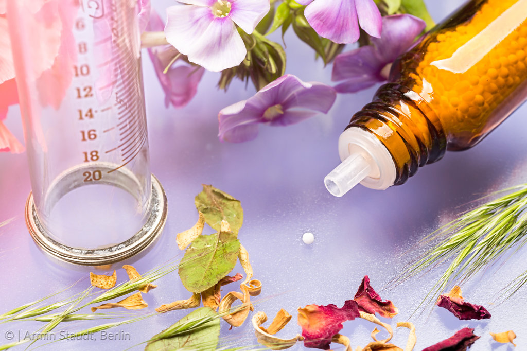 bottle with homeopathy globules, syringe and flowers