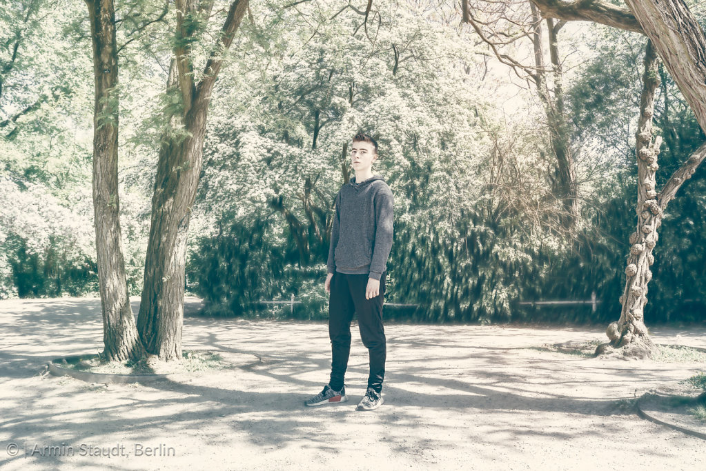 dreamy portrait of a standing young man in a park